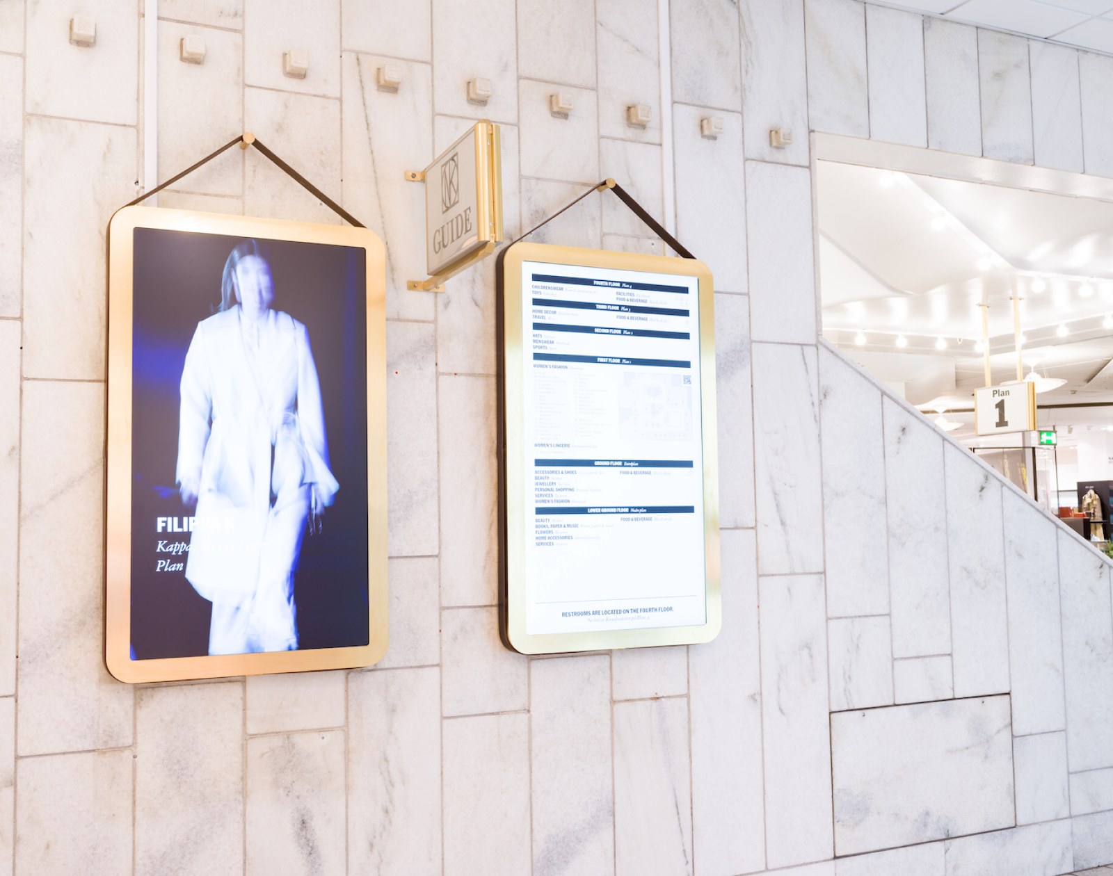 Wayfinding screens on a marble wall in a shopping centre
